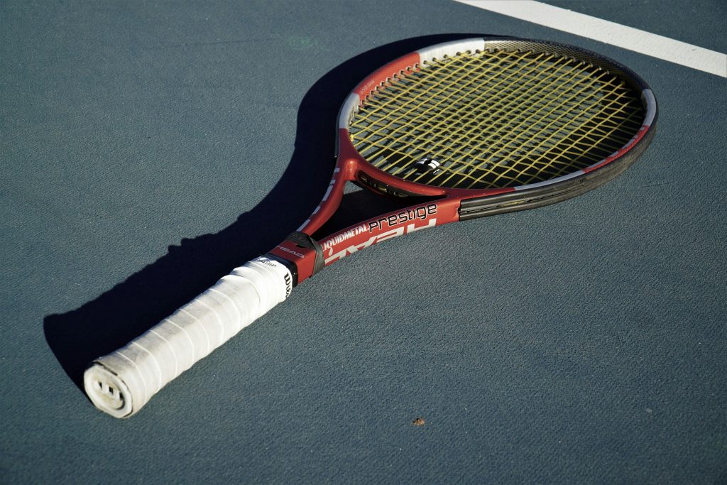 Raquette de tennis cordée posée sur un court - exemple de cordage et tension